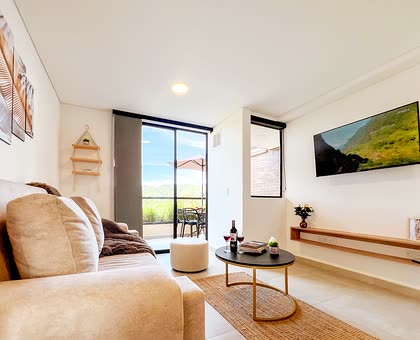 Sala con sofá, televisor y salida al balcón