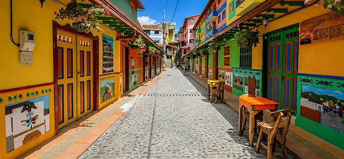 Calle de Guatapé con sus zócalos de colores y mesas en el andén