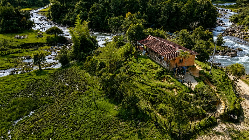 Casa campesina junto a la quebrada, rodeada de cultivos y bosque